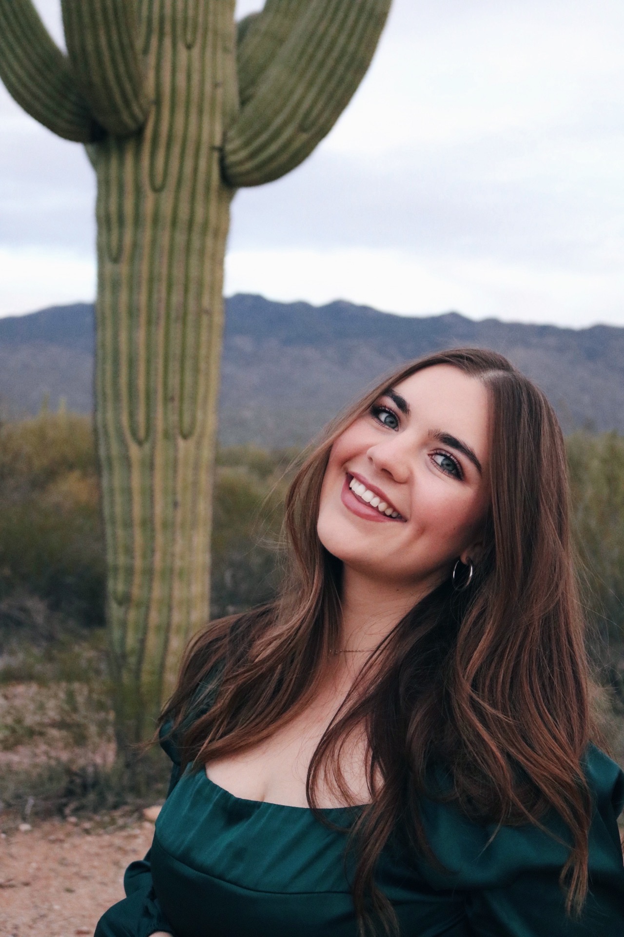 Savannah Hopkins, founder of Love at First Sip, smiling beside a saguaro cactus in the Tucson desert